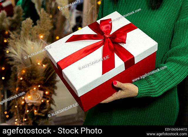 Woman in green sweater holding present. Christmas, New Year, Birthday, Valentines day concept