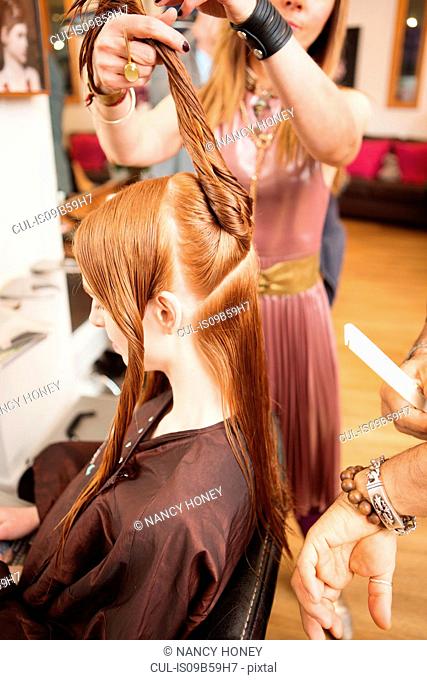 Female customer having long red hair twisted in hair salon