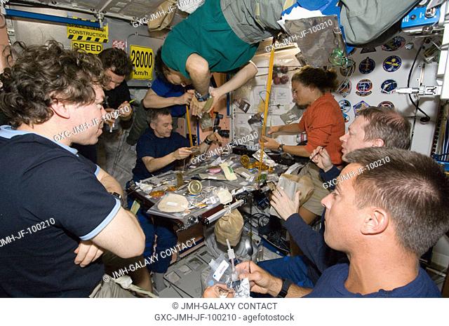 Eight of a total aggregation of 13 astronauts and cosmonauts are pictured at meal time aboard the International Space Station