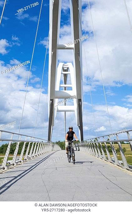 Female cyclist on The Infinity Bridge, which spans the river Tees at Stockton On Tees near Middlesbrough, north east England, United Kingdom, Europe
