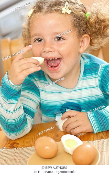 Adorable girl eating boiled eggs