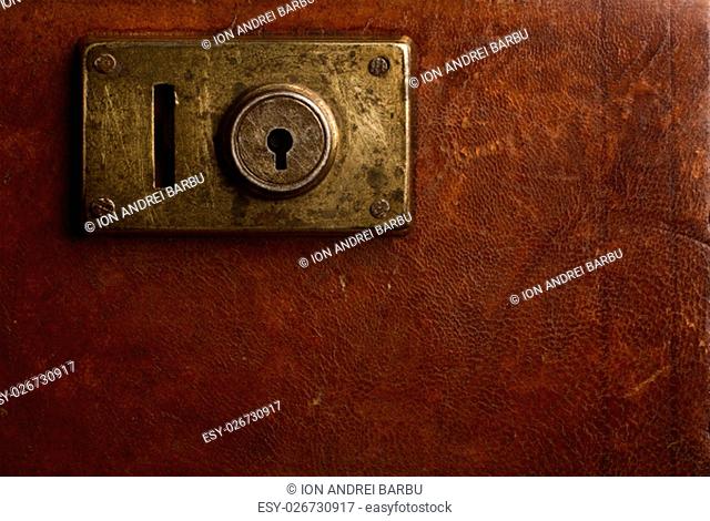 Horizontal close up of an old locking mechanism on a vintage suitcase made of brown leather