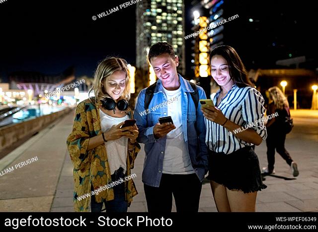 Smiling man and women surfing net through smart phone in city