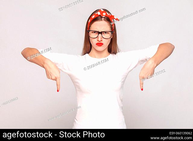 must be here right now. bossy anger portrait of beautiful emotional young woman in white t-shirt with freckles, glasses, red lips and head band