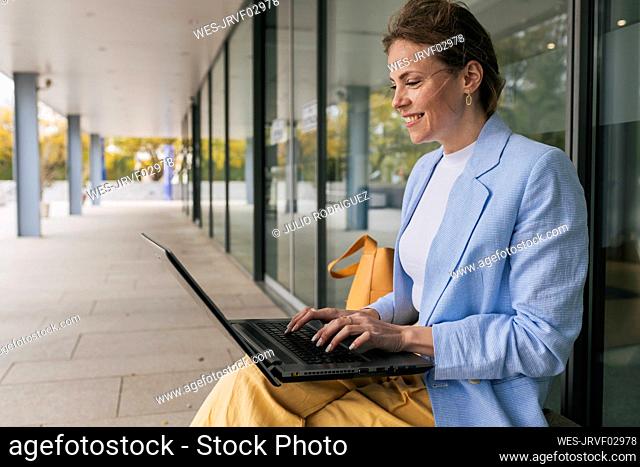 Freelancer using laptop sitting by glass window