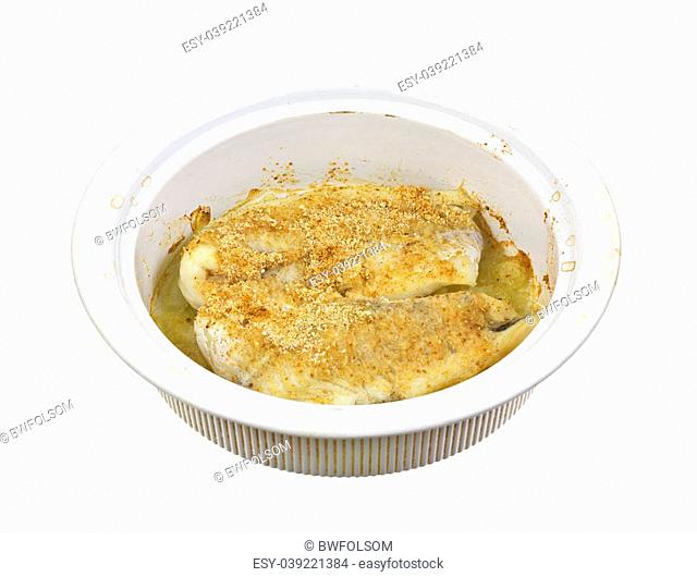 A home cooked meal of breaded haddock with onions in a ceramic baking dish