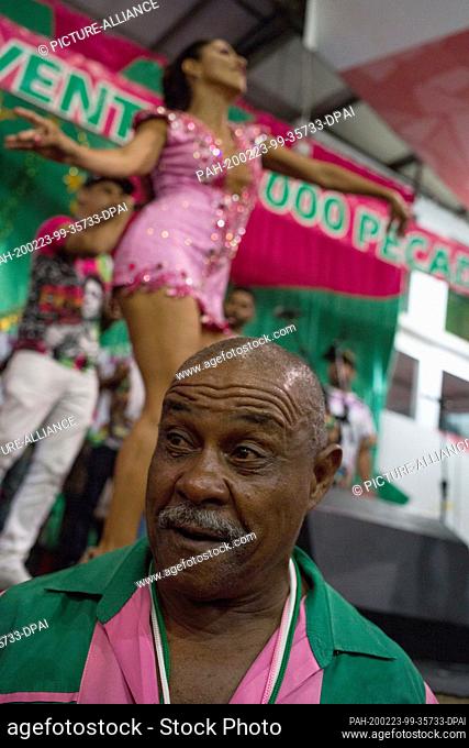 21 February 2020, Brazil, Rio de Janeiro: An older member of the school sings while a woman dances on stage at a rehearsal in the samba school ""Estacao...