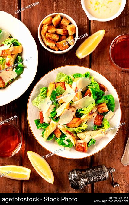 Caesar salad a rustic wooden table, with wine, lemon slices and croutons