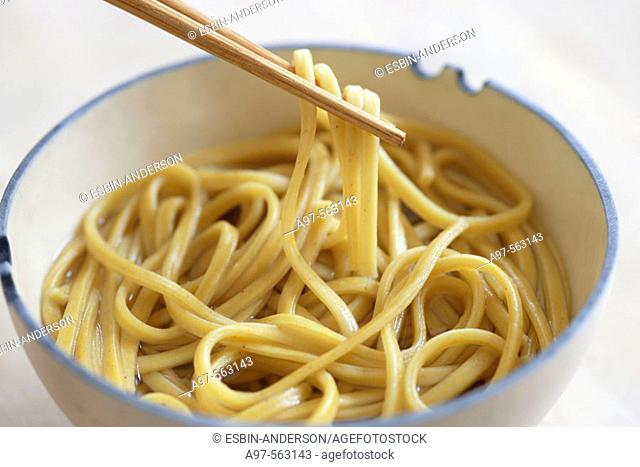 Asian noodles being lifted from a bowl by chopsticks