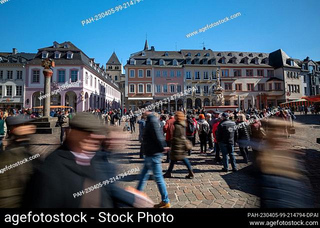04 April 2023, Rhineland-Palatinate, Mainz: A group of tourists stands at the Petrusbrunnen fountain on the main market square in the city center