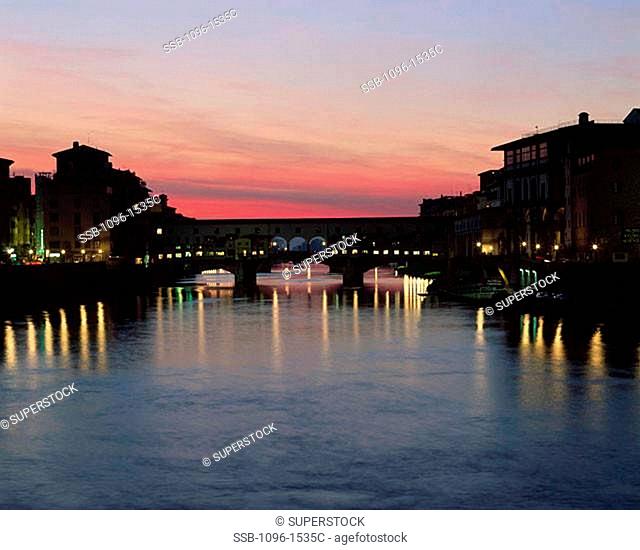 Silhouette of a bridge across a river lit up at dusk, Ponte Vecchio, Florence, Italy