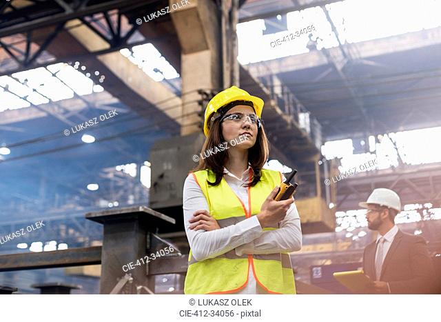 Female steel worker with walkie-talkie in factory