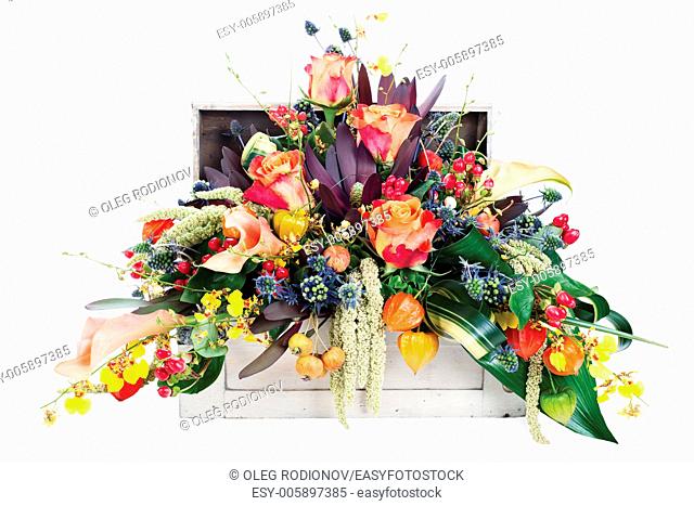 colorful floral arrangement of roses, lilies, freesia and irises in a wooden chest, isolated on white background