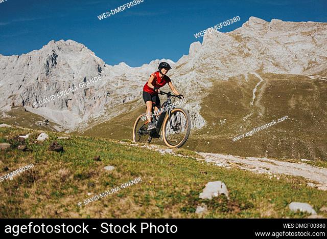 Female cyclist riding mountain bike on trail at Picos de Europa National Park, Cantabria, Spain
