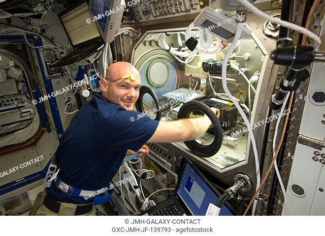 European Space Agency astronaut Alexander Gerst, Expedition 40 flight engineer, works with samples and hardware for a combustion experiment known as the Burning...