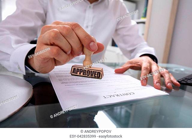 Businessman's Hand Stamping Approved On Contract Paper With Stamper