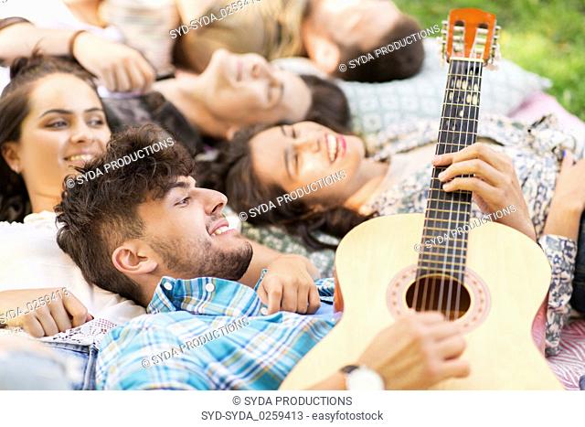 friends playing guitar and chilling on blanket