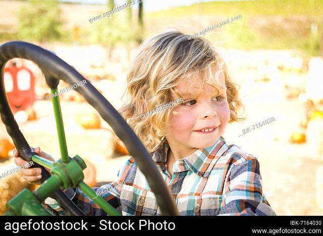 Little boy having fun in A tractor in a rustic ranch setting at the pumpkin patch