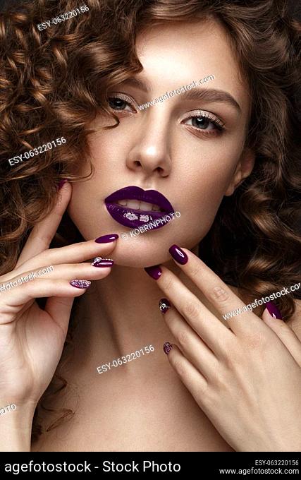 Beautiful girl with evening make-up, purple lips, curls and design manicure nails. beauty face. Photos shot in studio