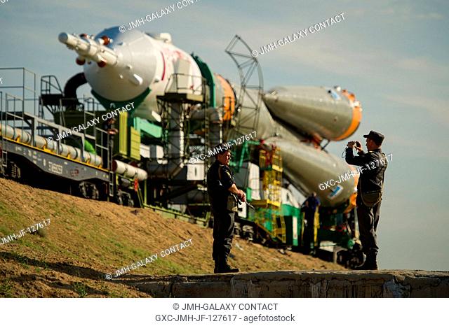 Russian security team members stop to take a photo as the Soyuz TMA-04M spacecraft is rolled out by train to launch pad one at the Baikonur Cosmodrome in...