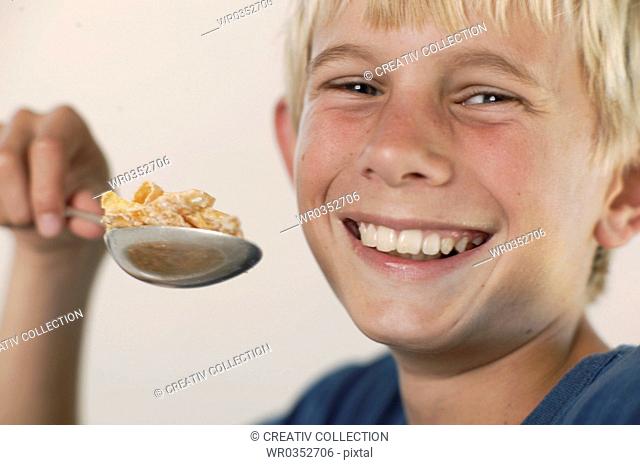 boy having muesli for breakfast smiling brightly