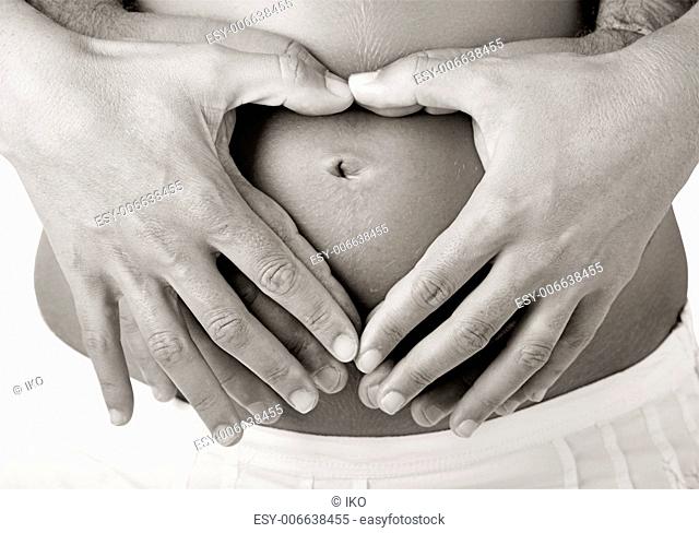Pregnant women wrap her arms around the belly in the form of the heart. Isolated on white