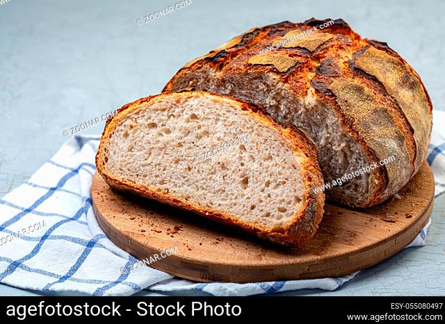 Sliced loaf of homemade country bread on a wooden board close-up, selective focus