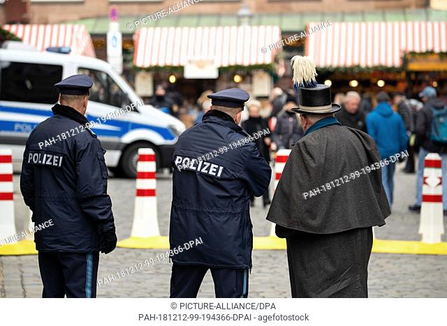 12 December 2018, Bavaria, Nürnberg: At Nuremberg's Christkindlesmarkt, policemen talk to a coachman from the old stagecoach at an access area
