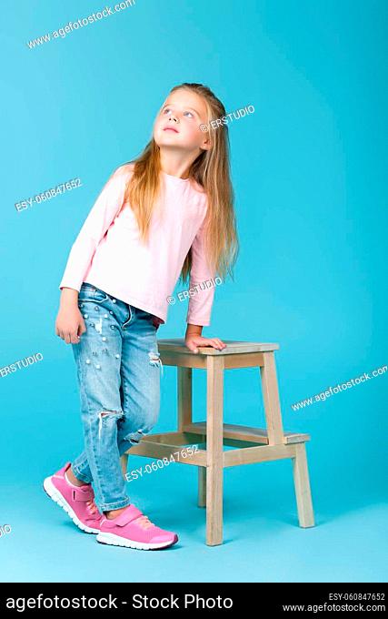 little beautiful girl in pink sweater and jeans posing in studio