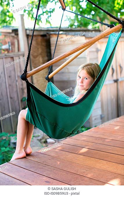 Portrait of girl looking over her shoulder from porch swing chair