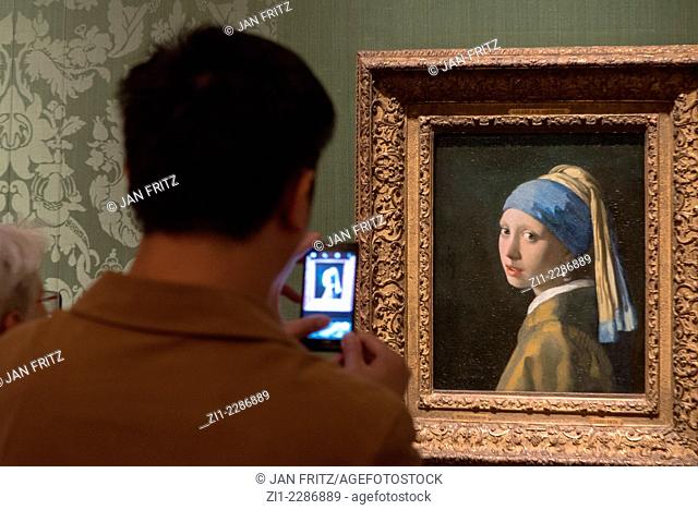 visitor taking photograph of famous painting 'girl with pearl earring' from Johannes Vermeer, 1666