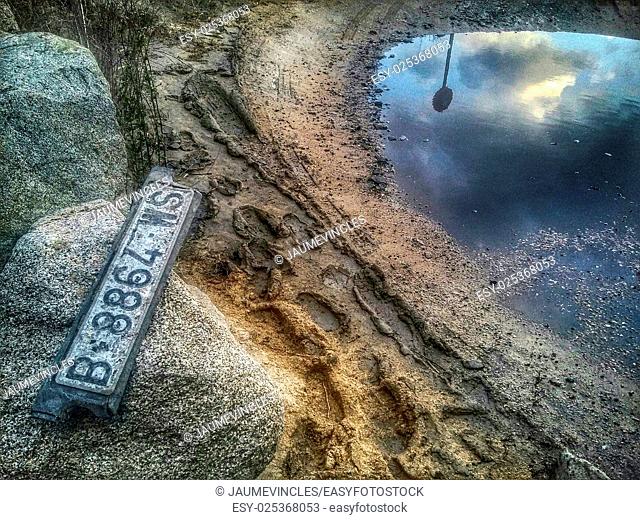 Abandoned car license plate and reflection in puddle. Arenys de Mar, Maresme, Barcelona province, Catalonia, Spain