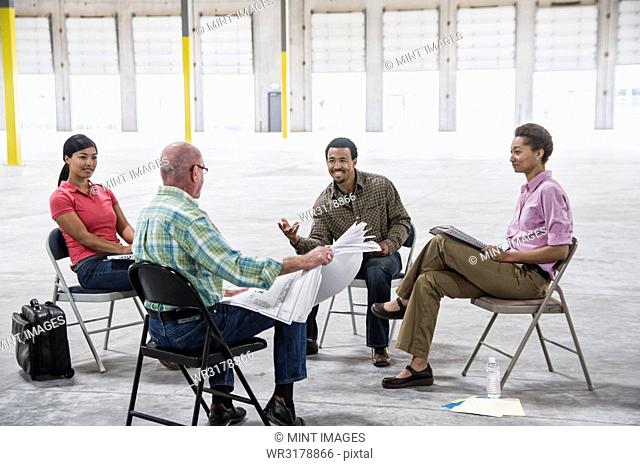 Multi-racial team of people going over plans for a new warehouse interior