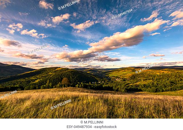 grassy slope in mountainous countryside at sunset. beautiful landscape with gorgeous cloudscape over the hills of Carpathian mountains