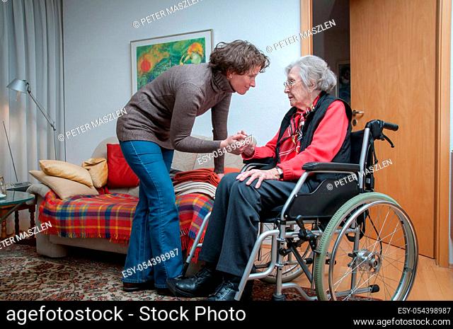 Caregiver woman holding hand of senior woman sitting in the wheelchair