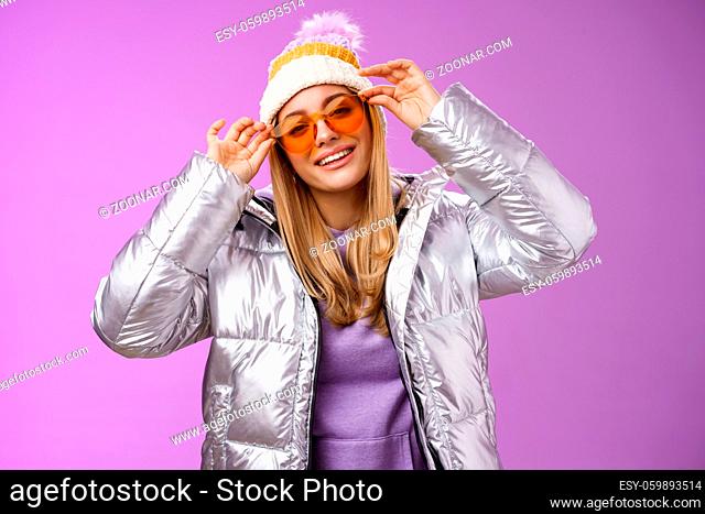Lifestyle. Stylish sassy daring blond european girl acting cool wear stylish sunglasses silver jacket winter hat checking frames nose tilting head cheeky...
