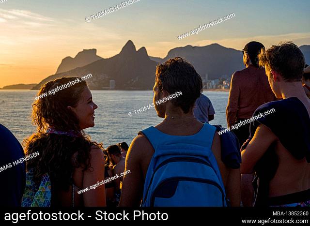 A magical place: People applaud when the sun sets at Arpoador rock with view of Ipanema beach and the Mountains of Morro Dois Irmaos and Leblon in the back