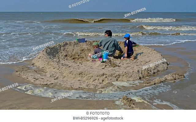 father and his two boys building a sand wall on the beach against the approaching flood, Germany, Mecklenburg-Western Pomerania, Zingst