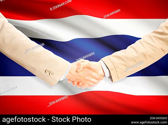 Businessmen shaking hands with flag on background - Thailand