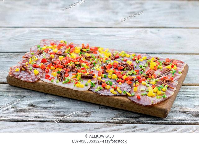 on a wooden board meat cutting and sausage with finely chopped vegetables