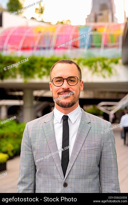Portrait of handsome Hispanic bald bearded businessman outside the building with modern architecture in the city outdoors