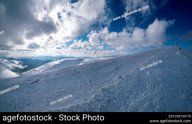 Snow and wind formed ice formations covered winter mountain plateau, tops with snow cornices in far. Magnificent sunny day on picturesque beautiful alpine ridge