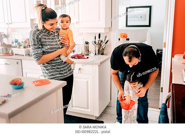Mid adult couple in kitchen with daughter and baby son