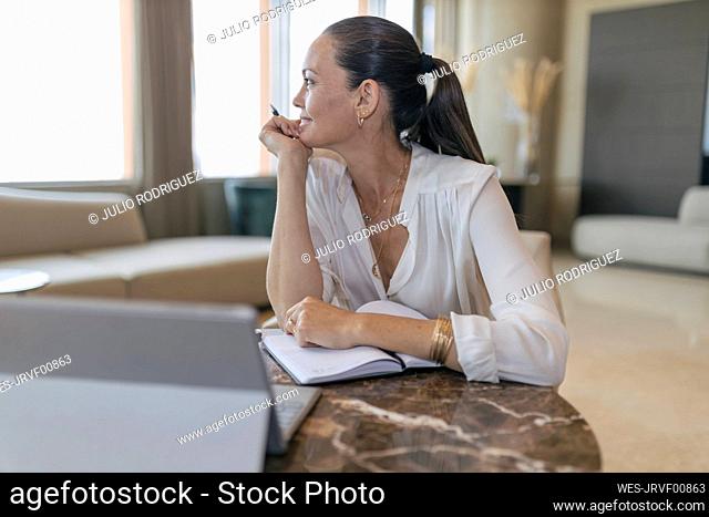 Thoughtful female professional sitting with diary at table in lobby