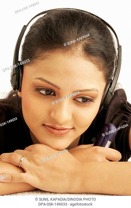 Maharashtrian teenage girl happily engrossed in listening to music using earphones MR686M