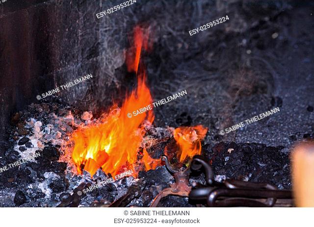 Embers and flame of a glowing red forge fire