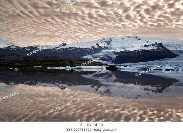 Reflections in Fjallsarlon lagoon in Iceland, by sunset