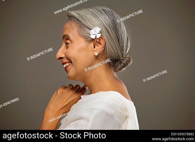 Portrait of old beautiful woman with a flower in her hair