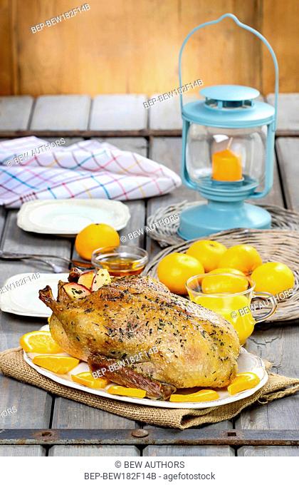 Roasted duck with oranges on wooden table