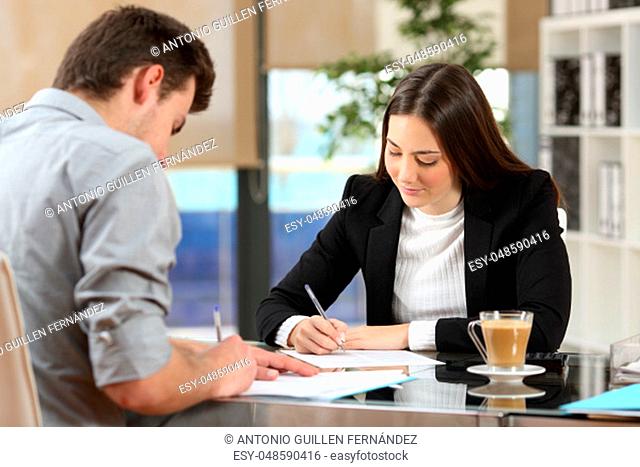 Businesspeople signing contracts together after a deal in a desktop at office